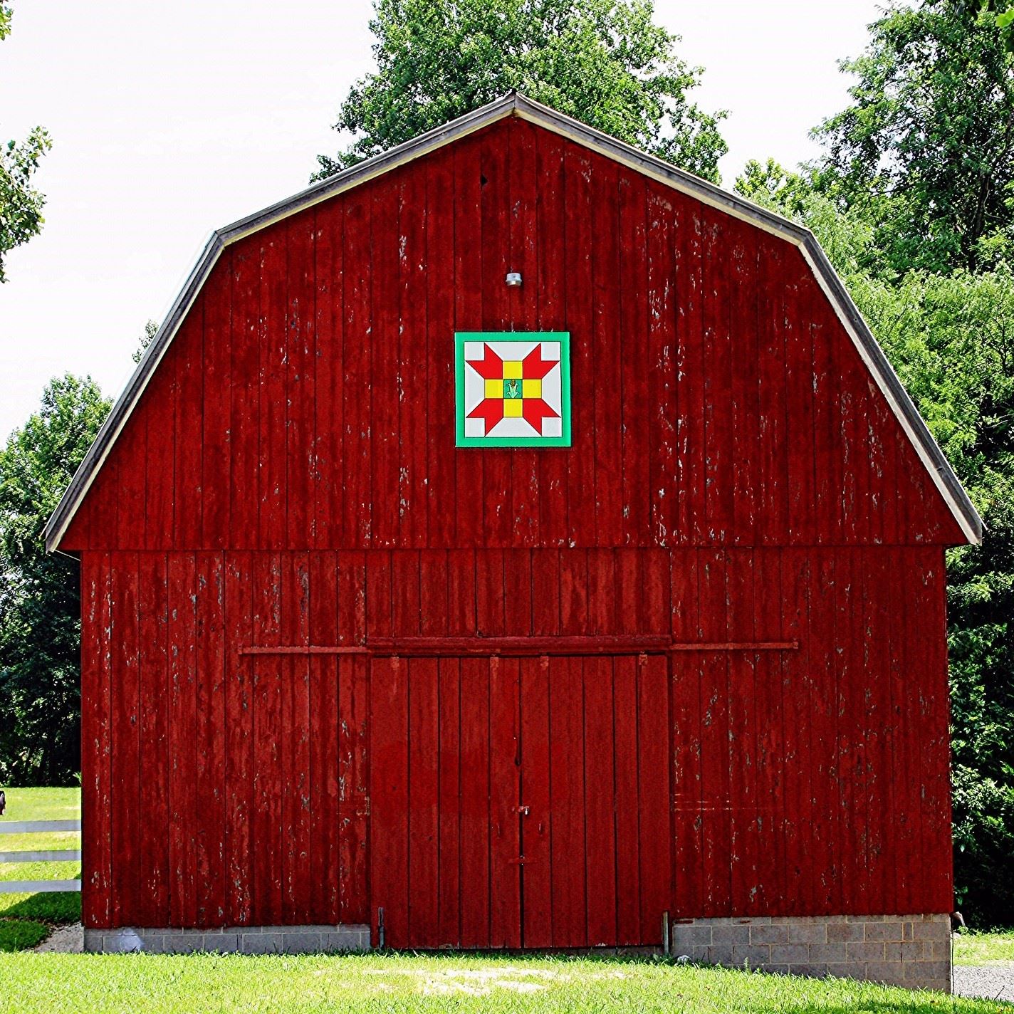 A large red barn with a quilt painted on it, part of the Barn Quilt Trail