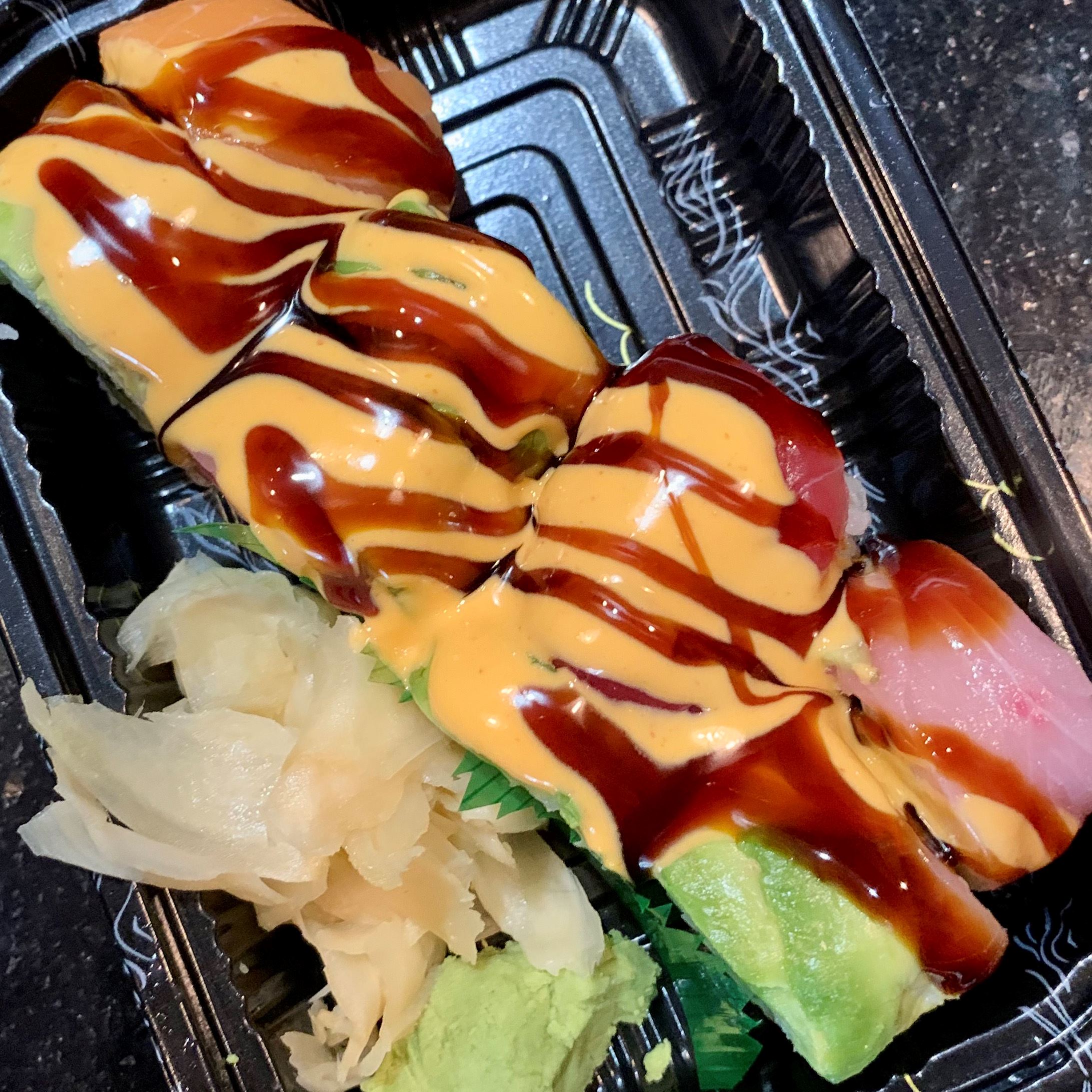 Asian food in a carry out container topped with sauces