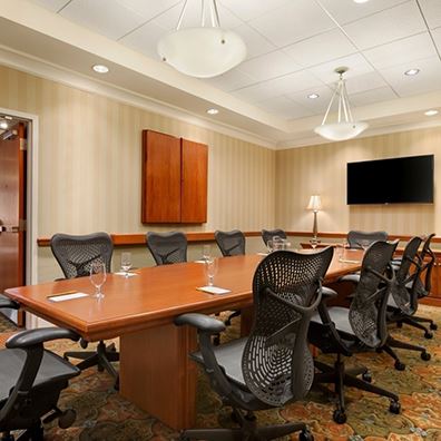 Hilton meeting rooms with chairs, a large table and a TV