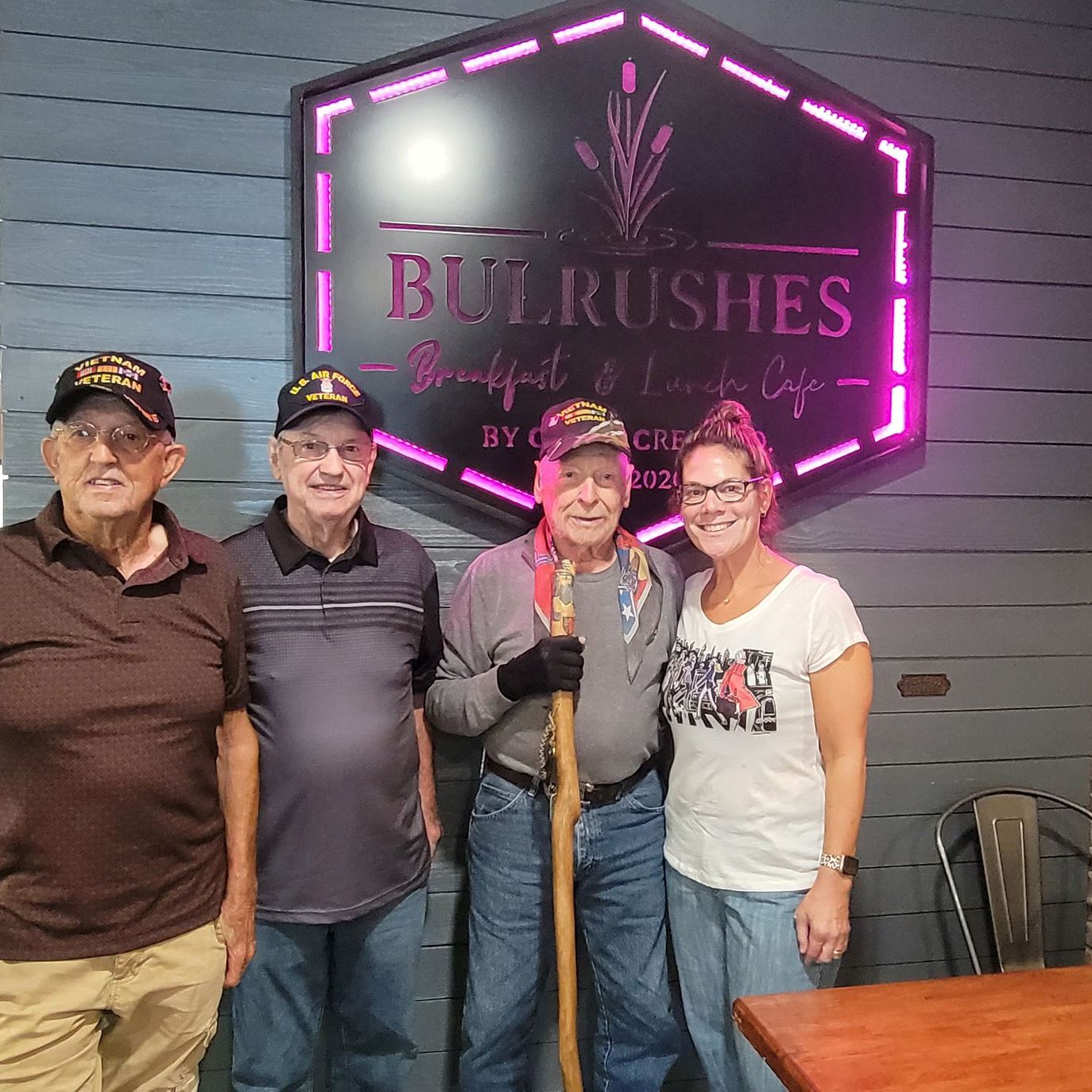 Veterans in front of a Bulrushes sign
