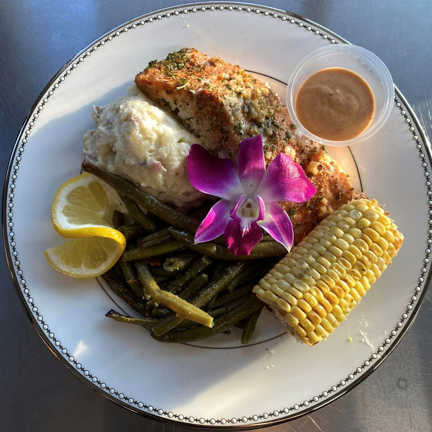 Salmon, corn, mashed potatoes, green beans and a purple flower