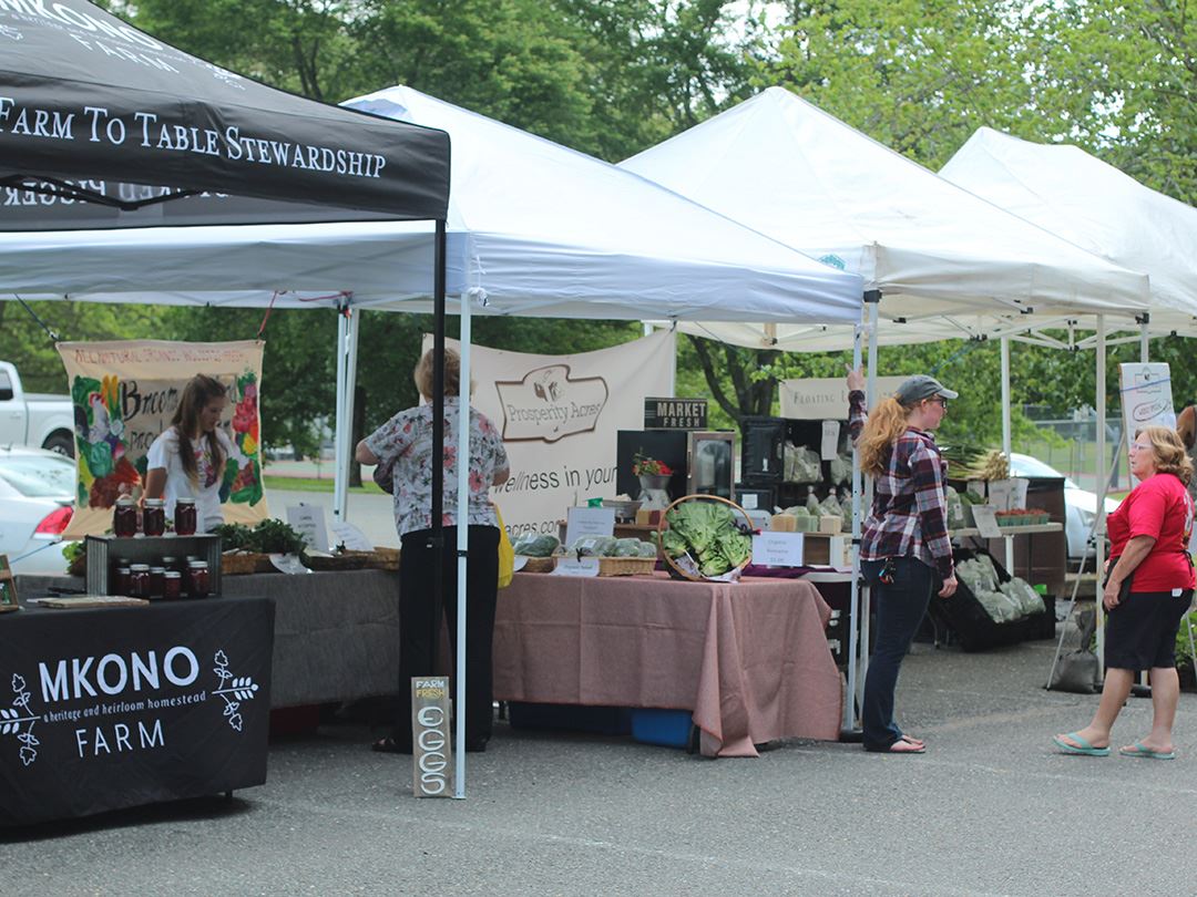 Tents selling fresh produce with patrons walking around