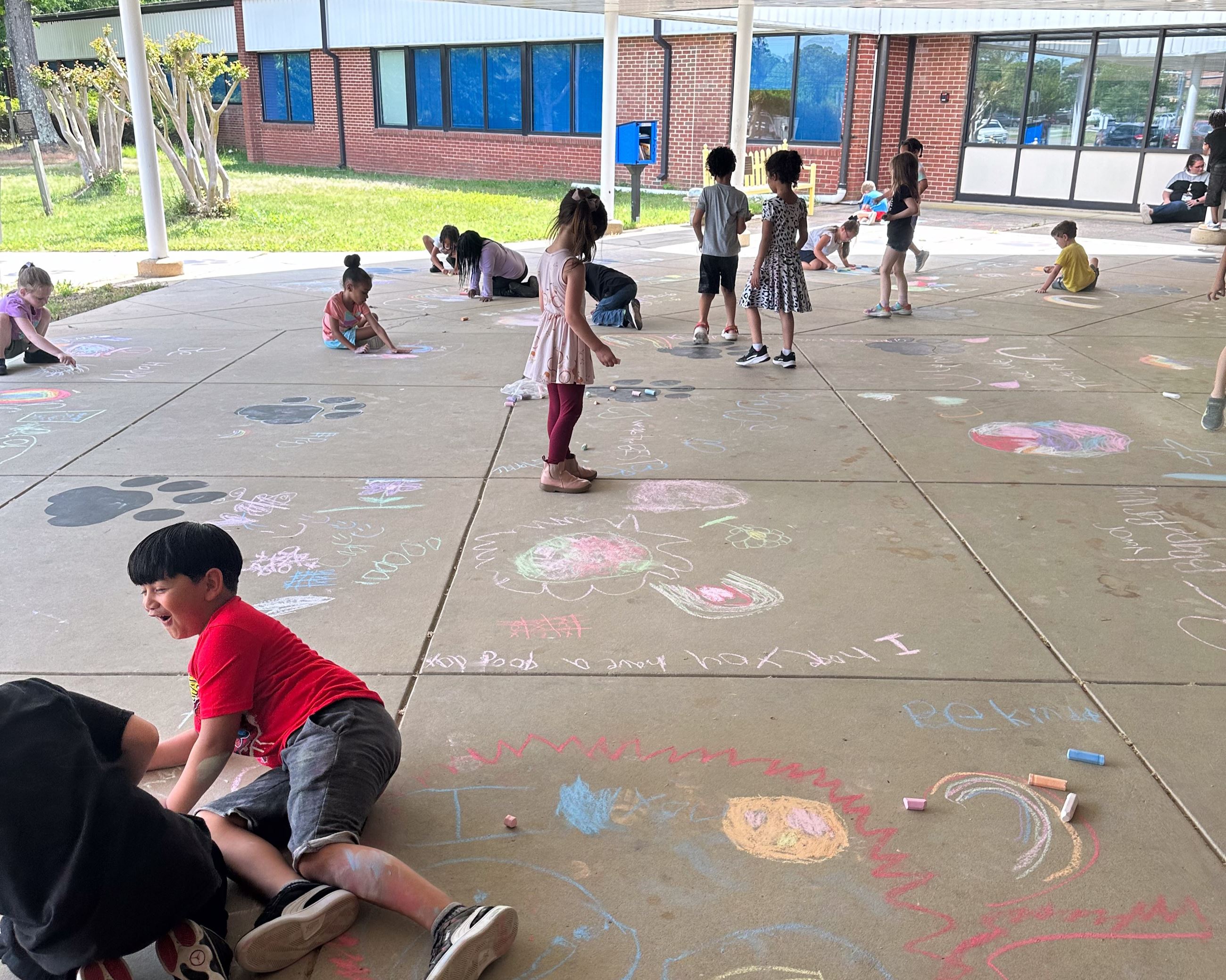 Large group of kids drawing with chalk in front of Patuxent Appeal Campus Elementary School.